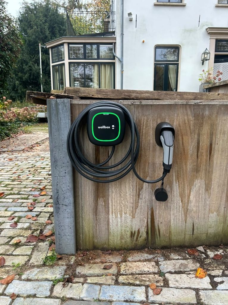 Wallbox laadpaal op een houten paal bij een woning in Beek